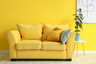 Şık oturma odasının içinde rahat bir kanepe, resim ve çiçek var.