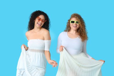 Mavi arka planda güneş gözlüklü güzel genç kadınlar.