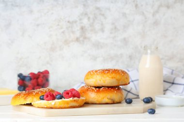 Beyaz ahşap masada meyveli ve tereyağlı lezzetli simit.