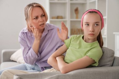 Evdeki kanepede oturan tartışan annesi yüzünden üzgün genç bir kız. Aile sorunları kavramı