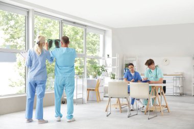 Olgun doktorlar, klinikte akciğerlerin röntgen görüntülerini inceliyor.