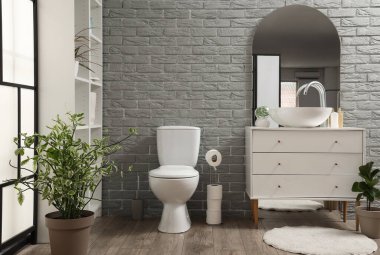 Modern tuvaletin içinde klozet, çekmecelerde lavabo ve ayna var.