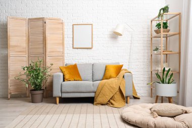 Gri kanepe, raf ünitesi ve bitkilerle oturma odasının içinde.