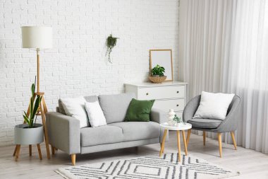 Gri kanepesi, koltuğu ve masası olan oturma odasının içinde.