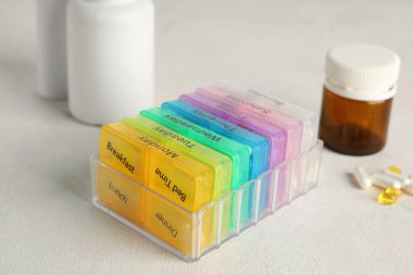 Beyaz arka planda plastik hap organizatörleri ve şişeler