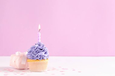 Beyaz masasında yanan mum ve hediye kutusu olan tatlı bir kek.