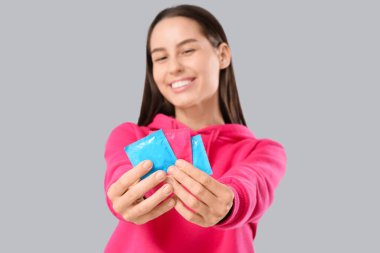 Ön planda kondomlar olan genç bir kadın, yakın plan.