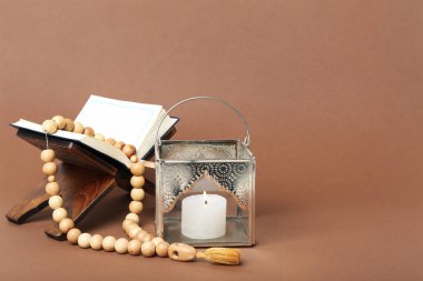 Kahverengi zemin üzerinde tespih ve Kur 'an olan Müslüman lambası