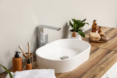 Kozmetik ürünleri şişeleri ve banyodaki ahşap masaya lavabo.