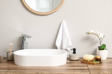 Modern lavabo, banyo malzemeleri ve banyo odunlarının yanındaki çekmecelerde saksı çiçeği.