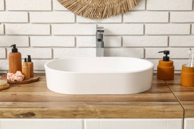 Lavabolu çekmeceler ve banyodaki beyaz tuğla duvarın yanında kozmetik ürünler.