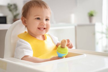 Mutfakta önlüklü ve kemirgenli şirin bir bebek, yakın plan.