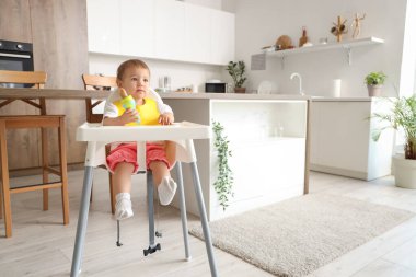 Cute little baby with nibbler in kitchen clipart