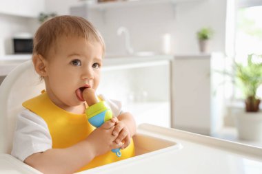 Mutfakta önlüklü ve kemirgenli şirin bir bebek, yakın plan.