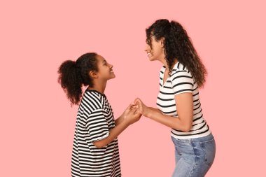 Güzel, genç, mutlu, Afro-Amerikan bir anne ve pembe arka planda kızı.