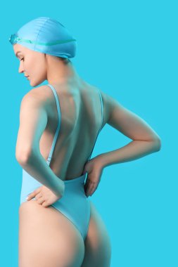 Mavi arka planda gerinen profesyonel genç bayan yüzücü