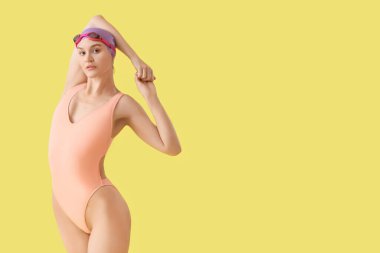 Profesyonel genç bayan yüzücü sarı arka planda geriniyor.