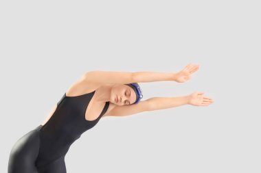 Gri arka planda gerinen profesyonel genç bayan yüzücü