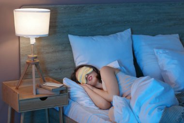 Maskeli genç ve güzel bir kadın geceleri yatak odasında uyuyor.