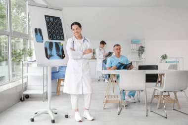 Klinikte röntgen görüntüleri olan bir kadın doktor var.