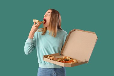 Young woman eating tasty pizza on green background