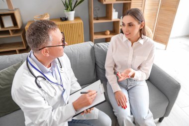 Olgun doktor evde hasta genç bayanı dinliyor.