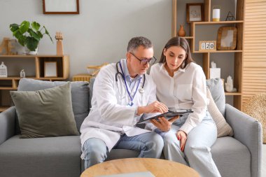 Olgun doktor evdeki hasta genç bayana panoyu gösteriyor.