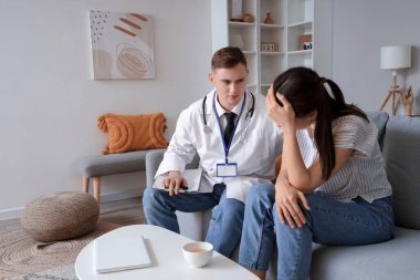 Erkek doktor, evde hasta genç bayanı teselli ediyor.