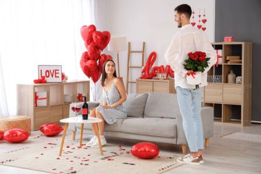 Genç bir adam evdeki kız arkadaşına gül ve hediye veriyor. Sevgililer Günü kutlaması