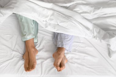 Genç bir çiftin ayakları yatağın üstünde, manzaralı.