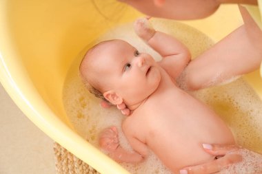 Evde banyo yapan, küçük şirin bir bebeği olan genç bir anne.