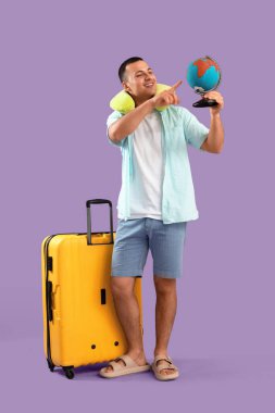 Bavullu bir erkek turist leylak arka plandaki küreyi gösteriyor.