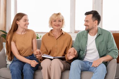 Ofisteki koltukta el ele tutuşan genç bir çiftle kadın psikolog.