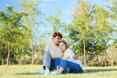 Güzel genç mutlu çift yaz parkında oturuyor.