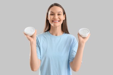 Arka planda diş pudrası dolu kavanozları olan genç bir kadın.