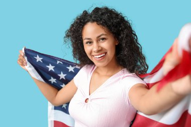 Mavi arka planda Amerikan bayrağı olan mutlu Afro-Amerikan kadın.