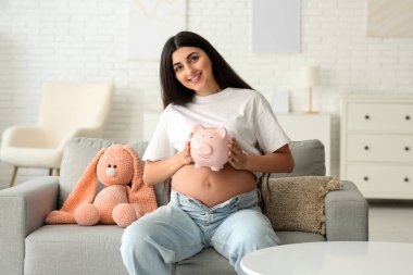Evdeki kanepede kumbaralı hamile bir kadın oturuyor. Annelik Faydası konsepti