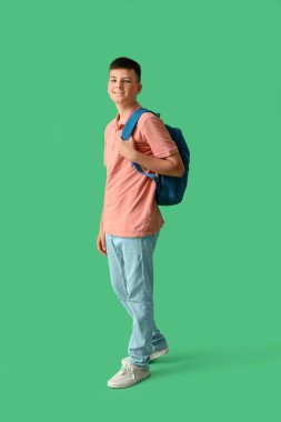 Teenage boy with backpack on green background