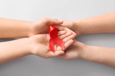 Gri arka planda kırmızı kurdeleli kadın eller. Kan Kanseri Farkındalığı Ayı