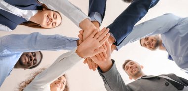 Bir grup iş adamı ofiste el ele tutuşuyor. Birlik kavramı