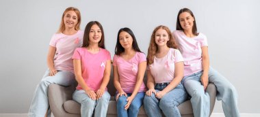 Pembe farkındalık kurdeleli kadınlar arka planda, koltukta oturuyorlar. Göğüs kanseri farkındalığı konsepti