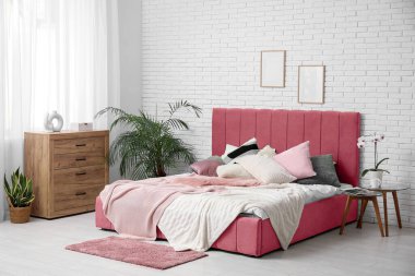 Yatağı, komodini, çiçekleri ve ahşap çekmeceleri olan modern yatak odası.