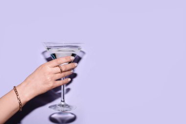 Leylak arkaplanda bir bardak martini olan bir kadın.