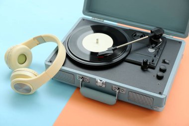 Renk arkaplanında vinil diski ve kulaklığı olan kayıt çalar, kapat