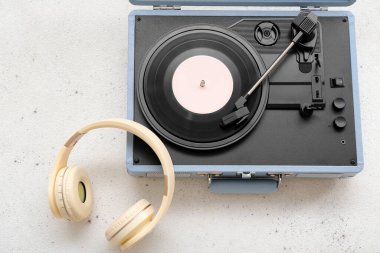 Açık arkaplanda vinil diski ve kulaklığı olan kayıt çalar