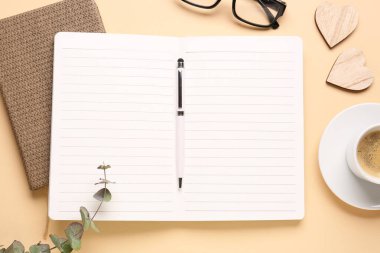 Boş defter, kahve fincanı ve bej arkaplanlı bardaklarla kompozisyon
