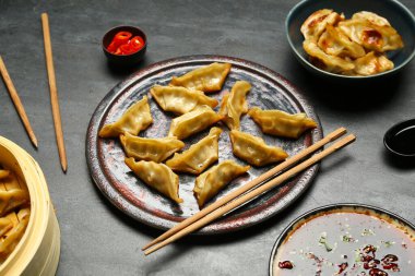 Lezzetli Çin jiaozi tabağı, bambu buharı ve siyah arka planda sos.