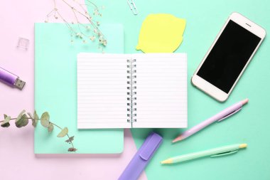 Renkli arka planda dizüstü bilgisayar, cep telefonu ve kalemlerle kompozisyon