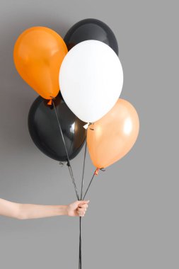 Gri arka planda farklı Cadılar Bayramı balonları olan kadın eli