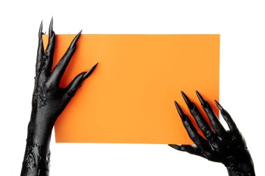 Beyaz zemin üzerinde boş turuncu kağıt çarşaf olan bir cadının kara elleri. Cadılar Bayramı